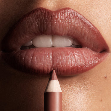 {Berry Cola} Morphe Signature Lip Pencil in Berry Cola applied on deep skin, close-up of full lined lips with pencil tip touching lower lip.