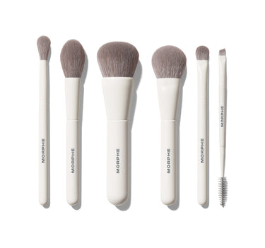 Along For The Glide 6 Piece Travel Brush Set featuring six white-handled MORPHE brushes with grey bristles laid flat, including eye, cheek, and dual-ended brow/liner tools. | Along for the Glide 6-Piece Travel Brush Set | Secondary image