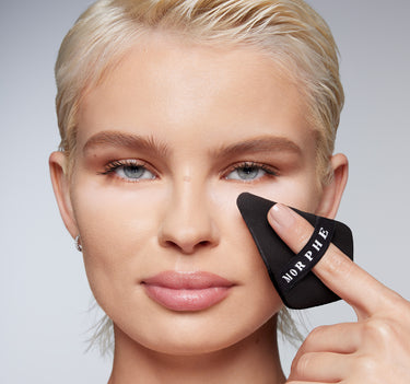 Blonde model applying Morphe Totally Set Mini Brighten & Set Powder Duo with black triangular sponge labeled MORPHE.