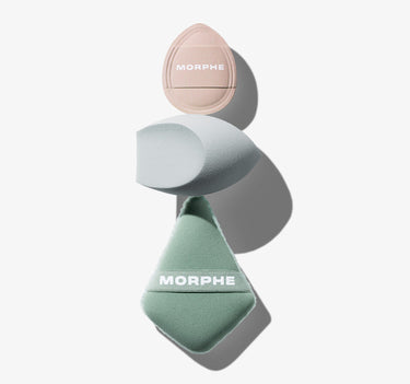 Morphe All Bases Covered 3 Piece Tool Set styled flat lay featuring a blush pink teardrop puff, a light blue oval sponge, and a sage green diamond puff — both the pink and green tools branded "MORPHE."