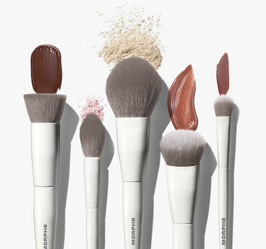 Portrait Mode 5 Piece Face Brush Set featuring five white MORPHE brushes styled with swirls of foundation, bronzer, and scattered pink and beige powder.
