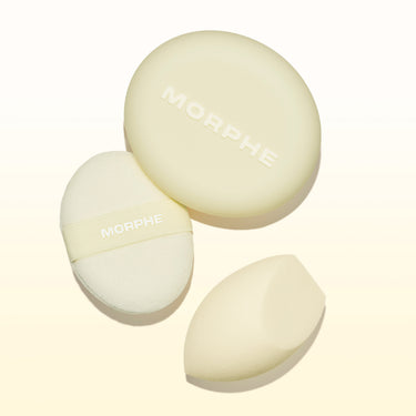 Morphe Buttery Blends Tool Duo stylized group shot showing a round MORPHE powder puff, a MORPHE-branded oval sponge with strap, and a teardrop blending sponge.