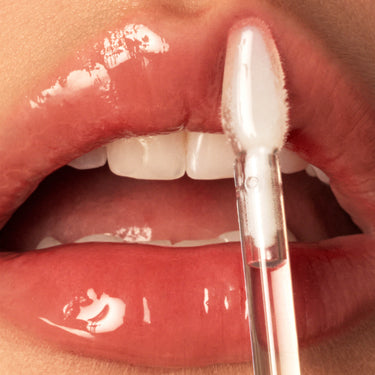 Close-up of lips being swiped with Morphe Dripglass Crystal lip gloss applicator wand for a glassy, high-shine finish.