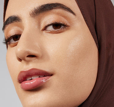 {Light 04W} Model wearing Lightform Extended Hydration Foundation in Light 04W, showcasing a luminous, dewy finish with bold brows and a glossy mauve lip.