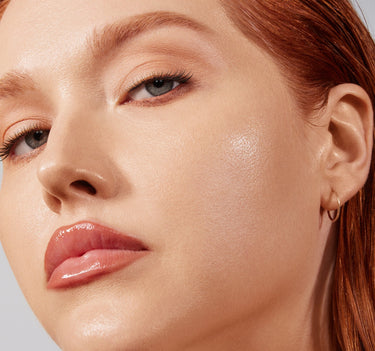 {Light 05N} Model wearing Lightform Extended Hydration Foundation in Light 05N, showcasing dewy, luminous skin with peachy-nude lip and reddish hair.