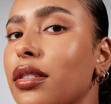{Tan 18W} Close-up model shot wearing Lightform Extended Hydration Foundation in Tan 18W, showcasing a dewy, luminous medium-warm complexion.