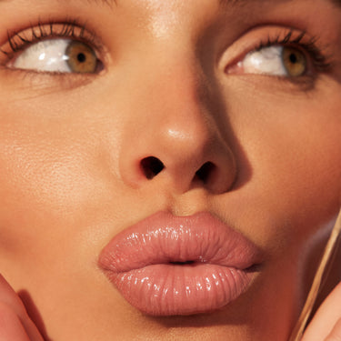 {Caught Rose} Liplock Glossy Lipstick campaign close-up showing full, glossy rose-pink lips on a model with glowing skin.