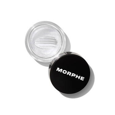 {Clear} Overhead shot of open glass jar of clear Supreme Brow Sculpting and Shaping Wax with black MORPHE-labeled lid beside it.
