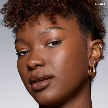 {Sunset} Model wear: woman with deep skin tone showing dewy, glowing complexion in Cloudlight Soft Glow Veil shade SUNSET
