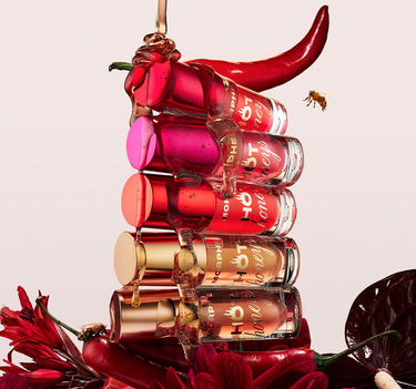 {Royal Sting} Five Hot Honeys Plumping Lip Oil tubes stacked with a red chili pepper on top, a bee, and red florals, each labeled "MORPHE Hot Honey."