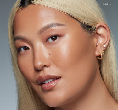 {Ignite} Model wearing Sudden Heat Creamy Bronzer Stick in shade IGNITE, a warm bronze finish bronzed across cheeks and skin.