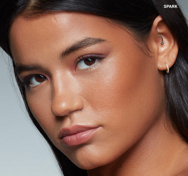 {Spark} Model wearing Sudden Heat Creamy Bronzer Stick in shade SPARK, showcasing a warm bronze glow on cheeks and skin.