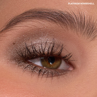 {Platinum Bombshell} Dazzling Metallics Eyeshadow Trio close-up eye macro showing shimmery platinum-taupe metallic shadow, with text "PLATINUM BOMBSHELL."