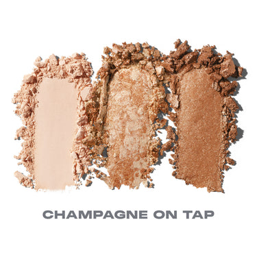 {Champagne On Tap} Dazzling Metallics Eyeshadow Trio powder smears in three shades — cream, champagne gold, and bronze — with text "CHAMPAGNE ON TAP."