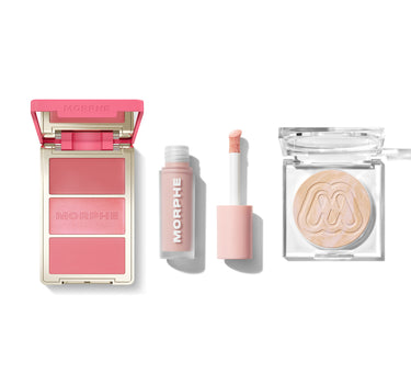 Morphe Ultimate Glow Trio with open MORPHE-engraved blush compact showing three rosy pink shades, a MORPHE lip gloss with applicator, and a clear highlighter compact with embossed M logo. | Ultimate Glow Trio