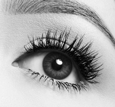Black-and-white close-up of eye with thick, voluminous Morphe Make It Big Mini Volumizing Mascara lashes flared out.